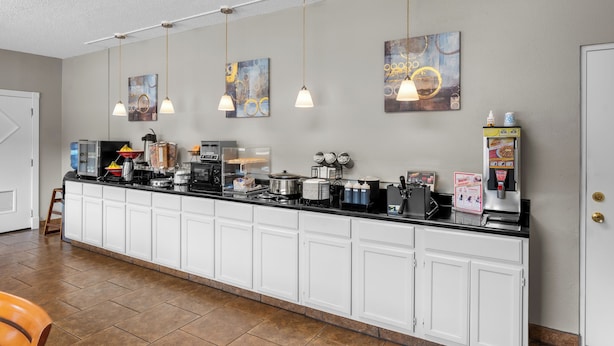A kitchen with white cabinets, a black countertop, and hanging pendant lights. There are several appliances, including a coffee maker and a toaster. - Rodeway Inn Hot Springs National Park Area (Hot Springs)