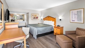 A hotel room with a bed, a desk, a chair, a sofa, and a TV. - Rodeway Inn Hot Springs National Park Area (Hot Springs)