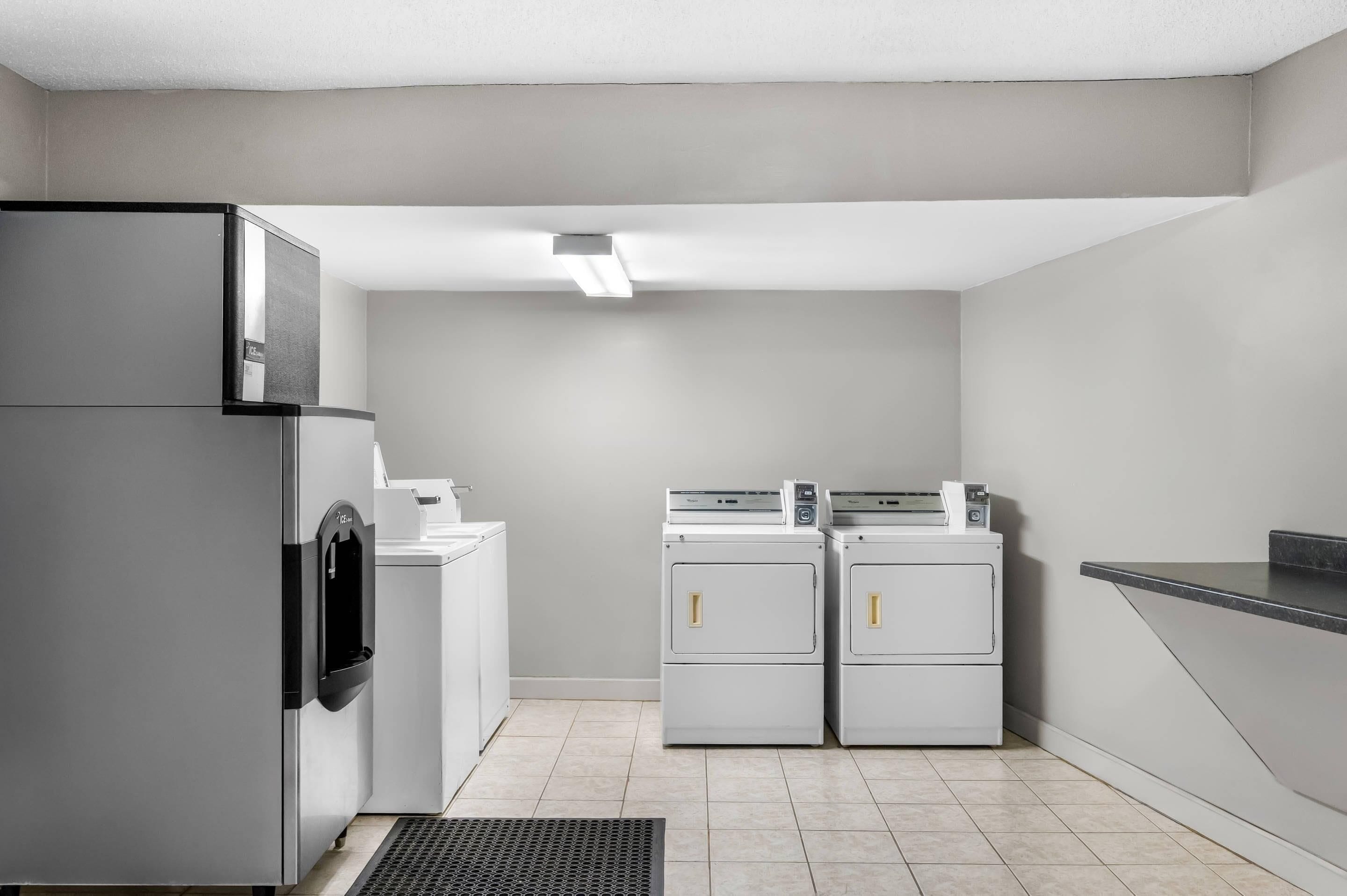 A laundry room with a refrigerator, washing machines, and a sink.
