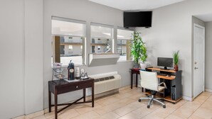 A modern office space with a desk, chair, computer, and a large window with a view of a building. - Rodeway Inn Hot Springs National Park Area (Hot Springs)