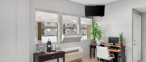 A modern office space with a desk, chair, computer, and a large window with a view of a building.