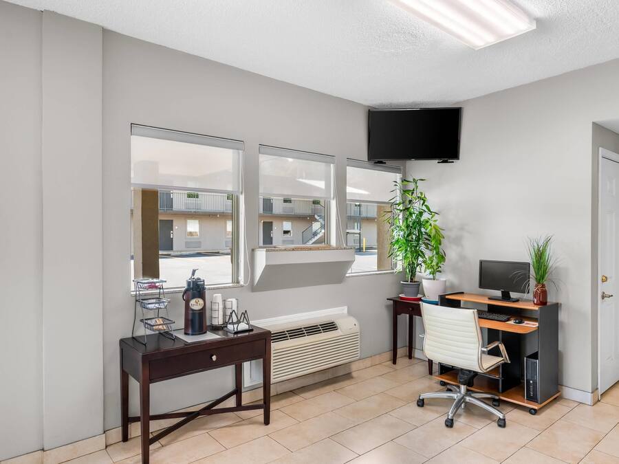 A modern office space with a desk, chair, computer, and a large window with a view of a building.