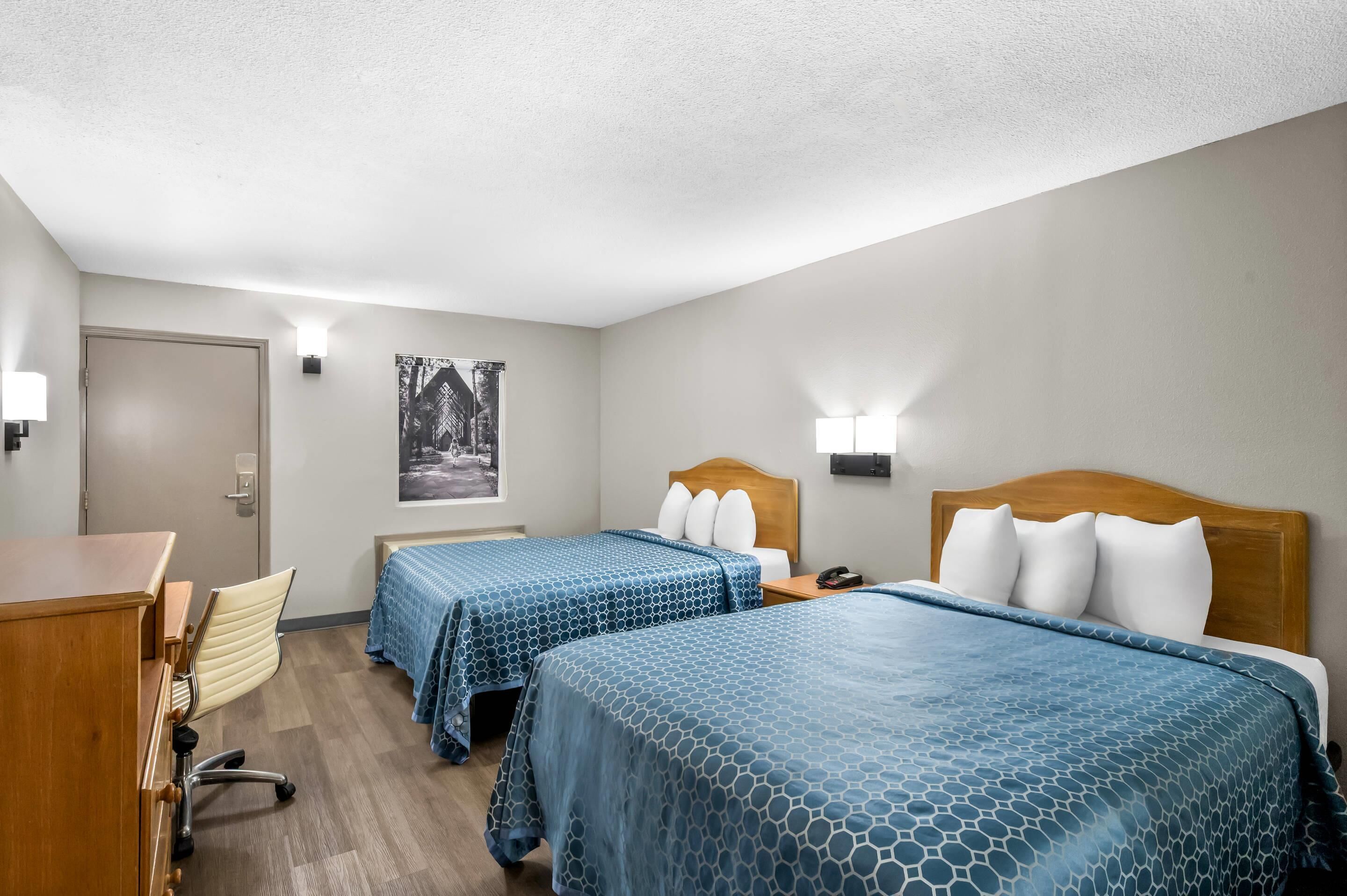 Habitación de hotel con dos camas, un escritorio, una silla y una puerta.