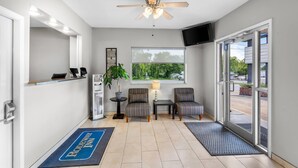 A hotel lobby with a reception desk, seating area, ceiling fan, large window, and a view of the outside. - Rodeway Inn Hot Springs National Park Area (Hot Springs)