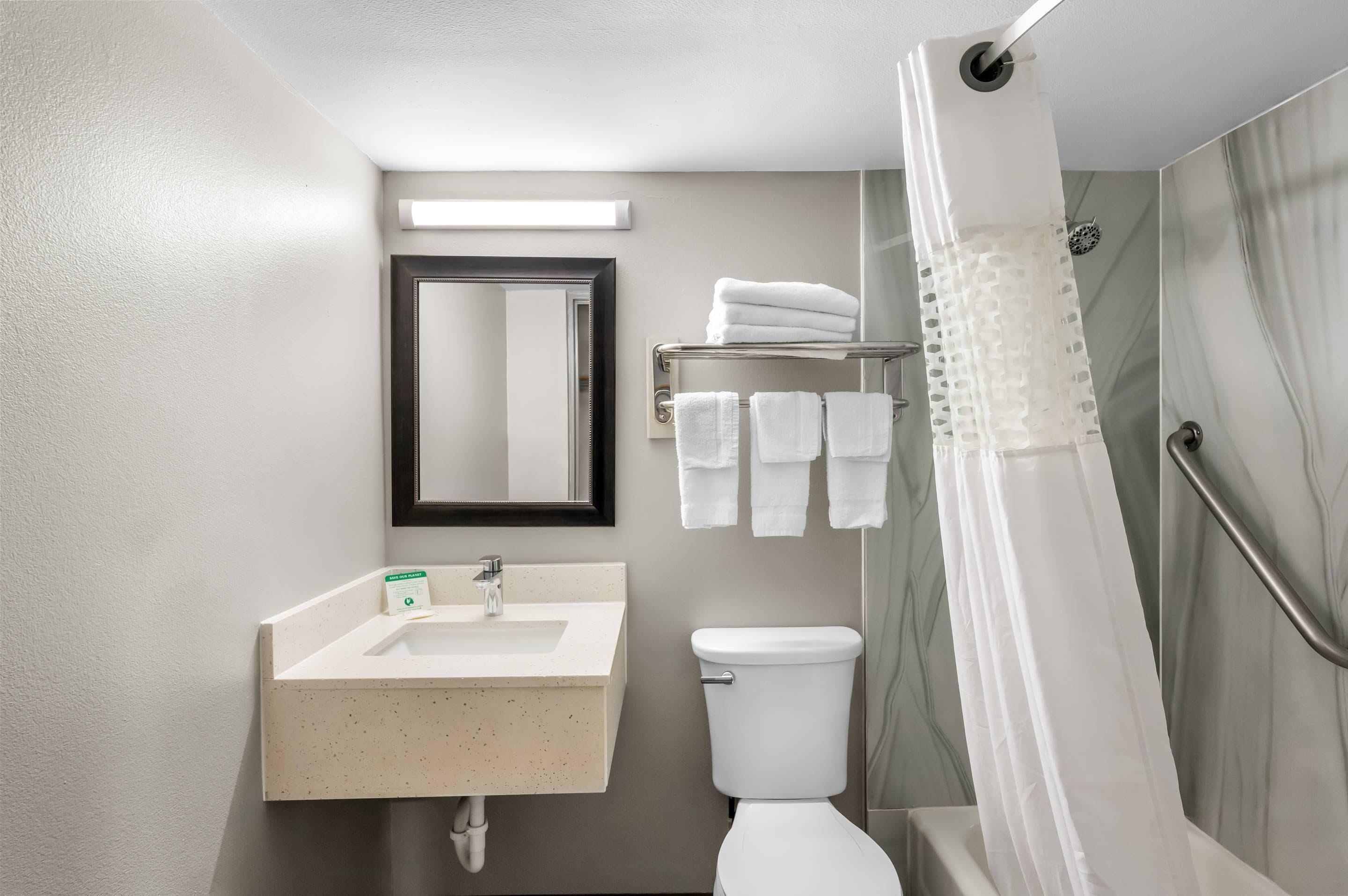 Un baño moderno con lavamanos, inodoro y zona de ducha.