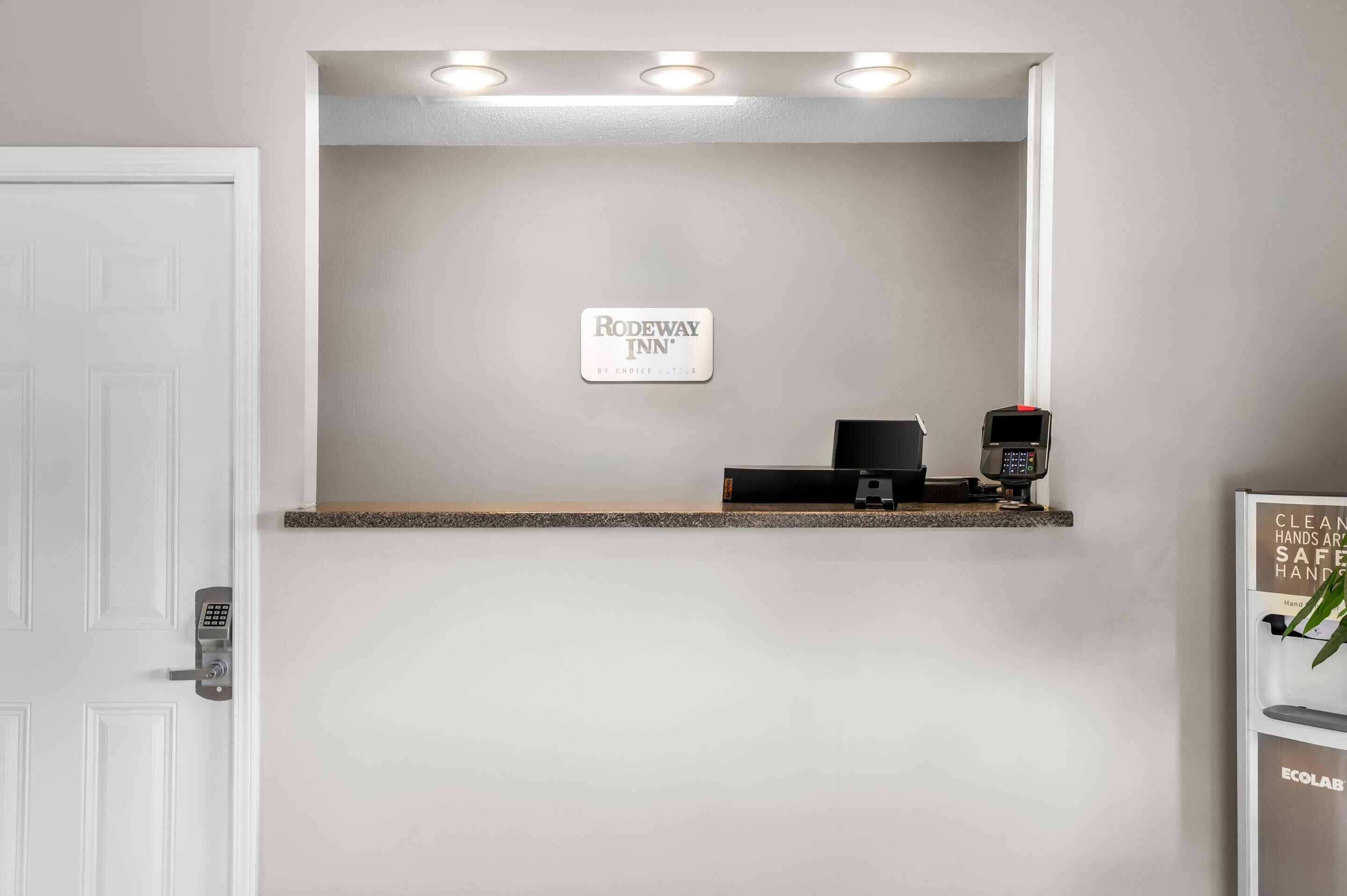 A reception desk with a sign for 'Rodeway Inn' and a digital payment terminal.