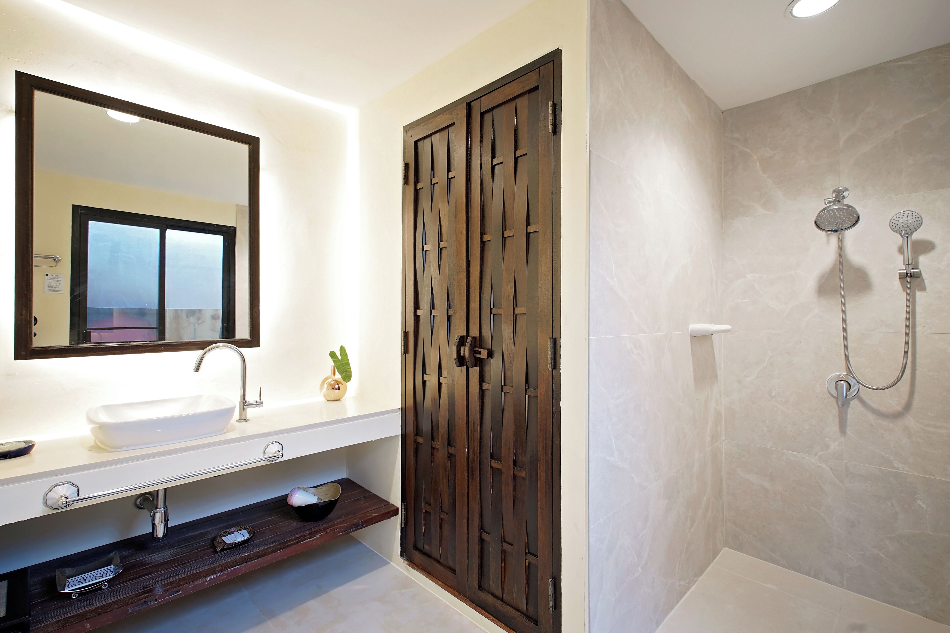 A bathroom with a white sink, a mirror, a wooden door, and a shower area.