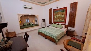 A bedroom with a bed, a window seat, a desk, and a chair. - HOTEL MAHENDRA PRAKASH (Udaipur)