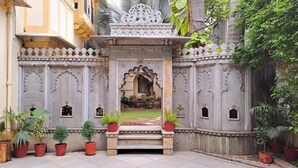 A traditional entrance with ornate carvings, a small archway, and potted plants. - HOTEL MAHENDRA PRAKASH (Udaipur)