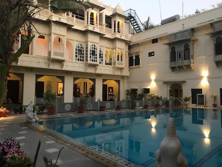 Una piscina al aire libre, sombrillas. HOTEL MAHENDRA PRAKASH