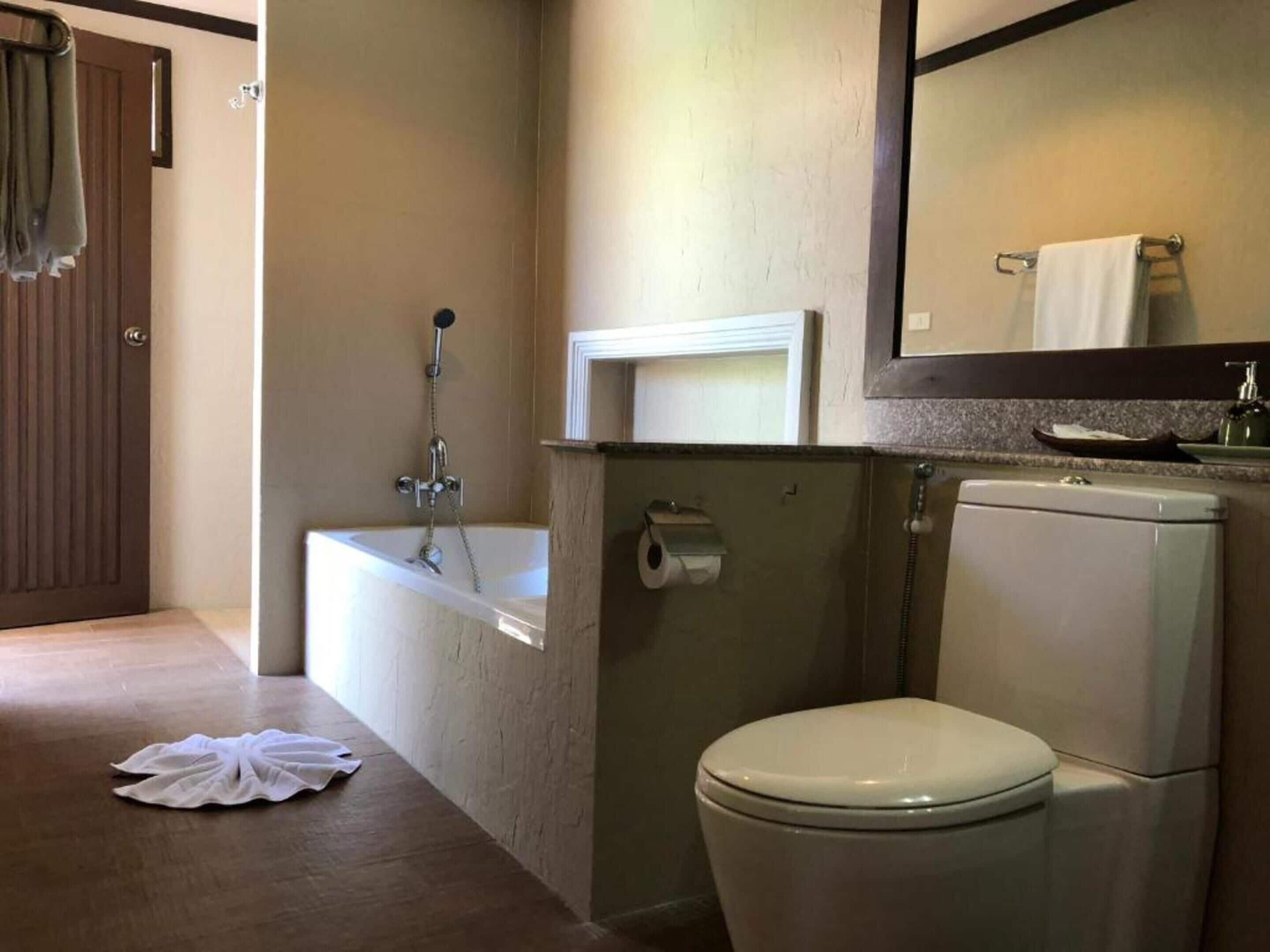A bathroom with a bathtub, toilet, and a towel rack.