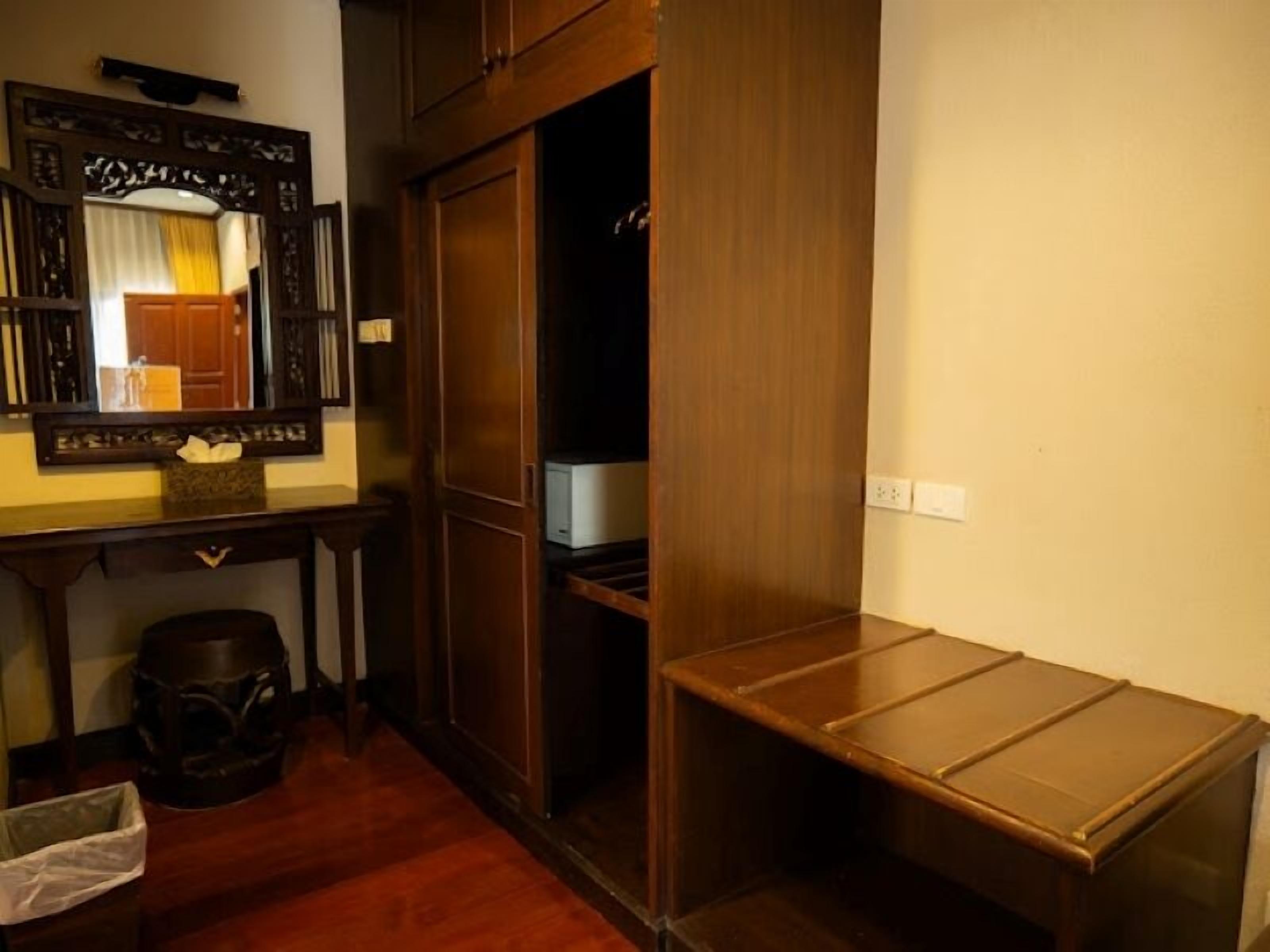 Une pièce avec un bureau en bois, un miroir et une armoire.