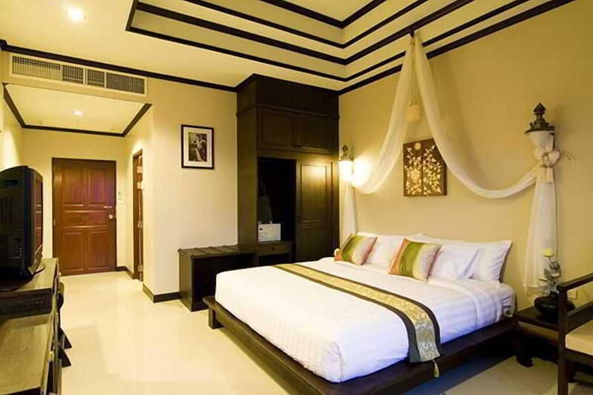 A hotel room with a large bed, a television, a wardrobe, and a desk.