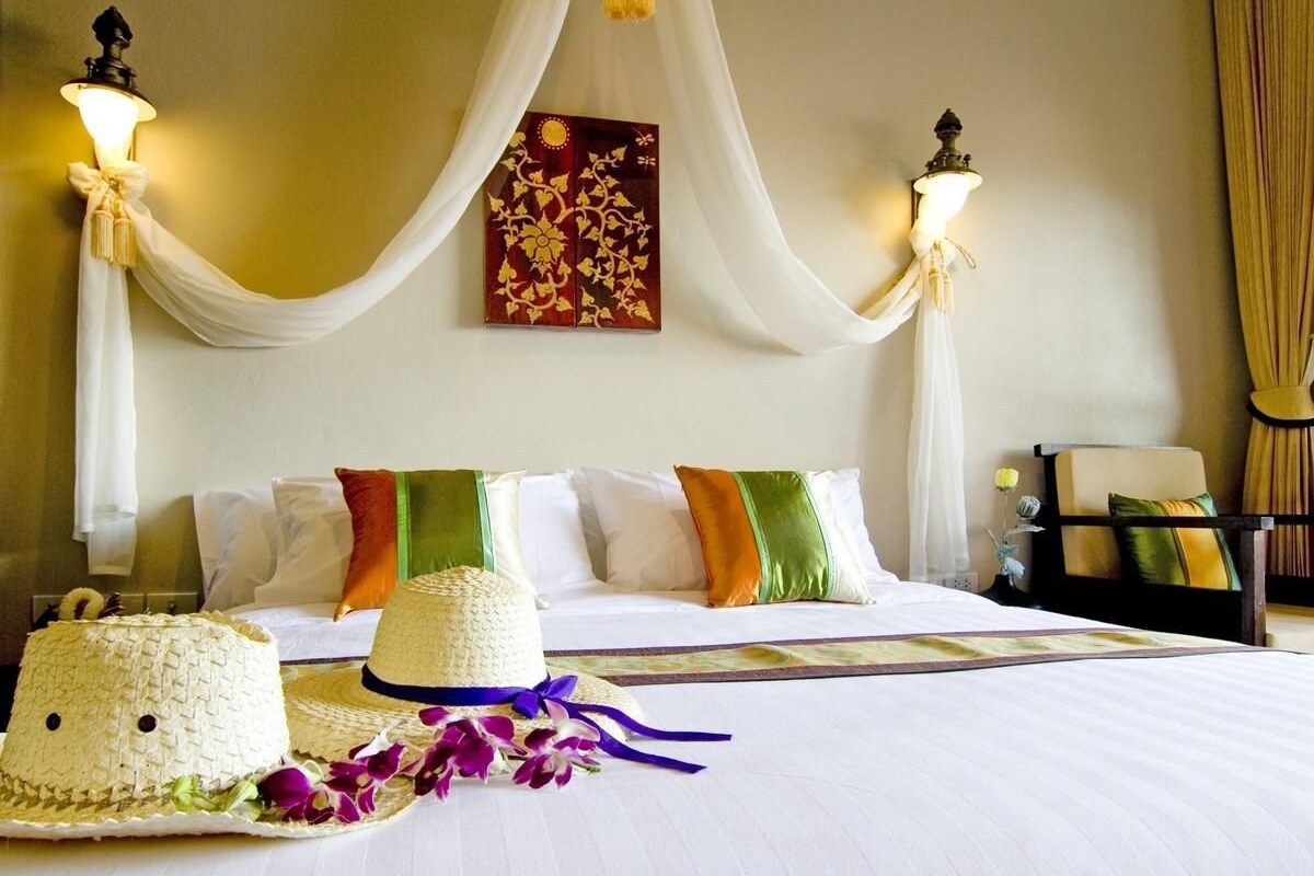 A hotel room with a large bed, two wall-mounted lamps, a painting, and a chair.