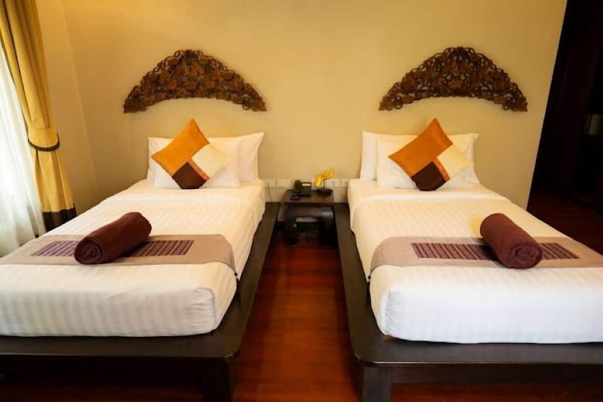 Two adjacent beds with white linens, brown towels, and decorative wall art above them.