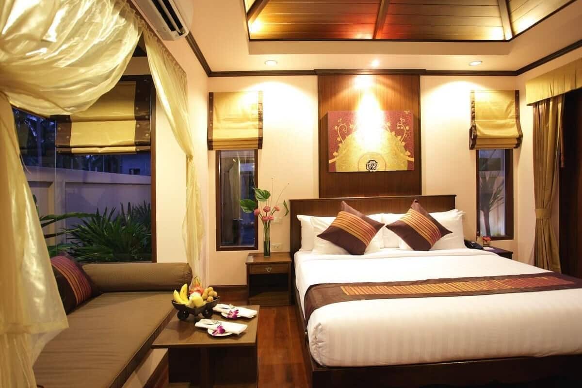 Una habitación de hotel con cama, mesitas de noche, sofá y ventana con cortinas.