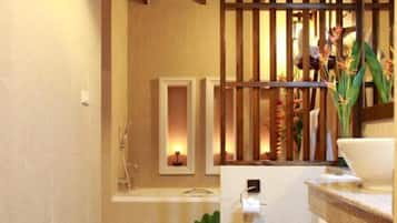 A modern bathroom with a wooden ceiling, a white toilet, a sink with a mirror, and a small plant.