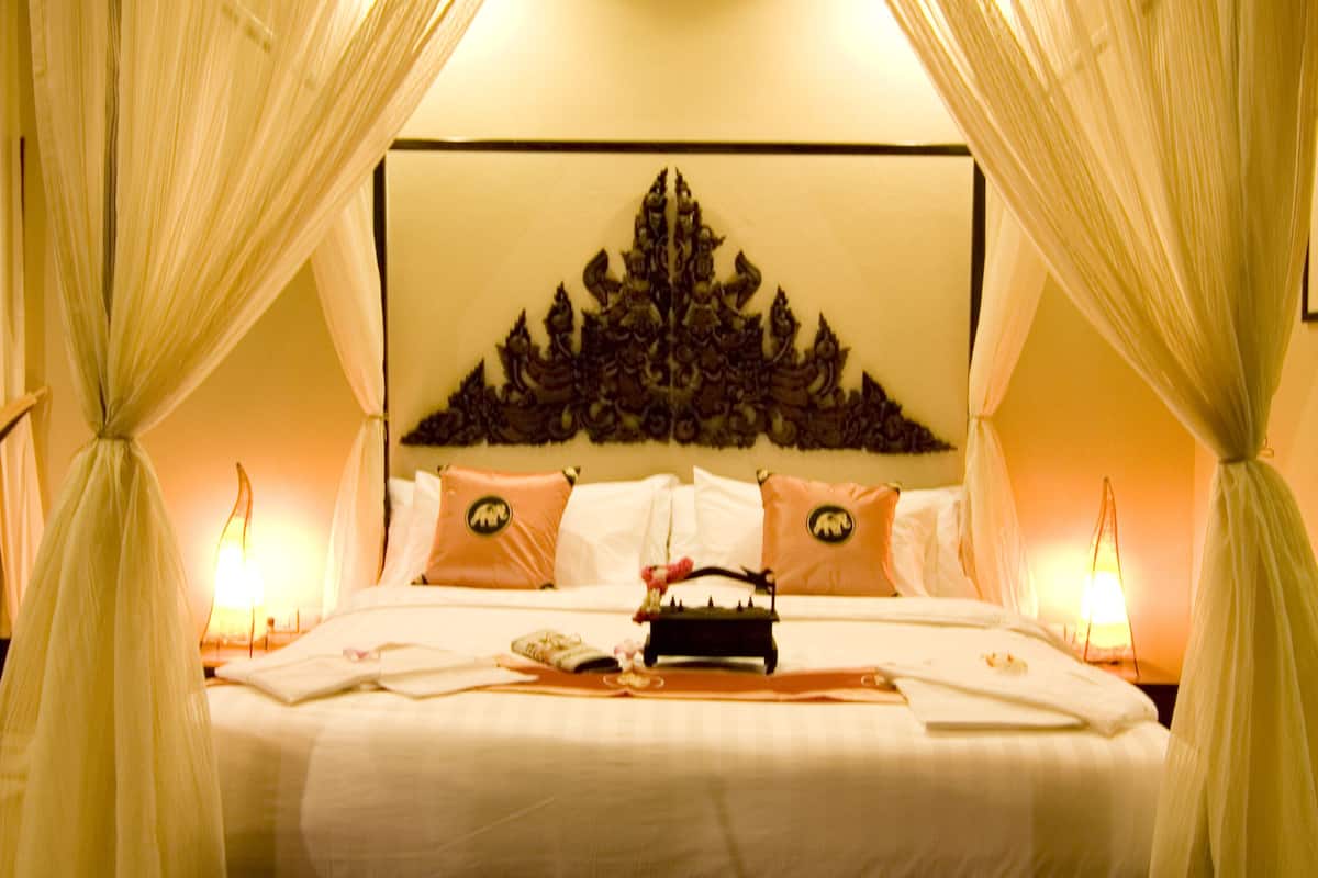 A neatly made bed with a headboard, pillows, and a tray of toiletries.