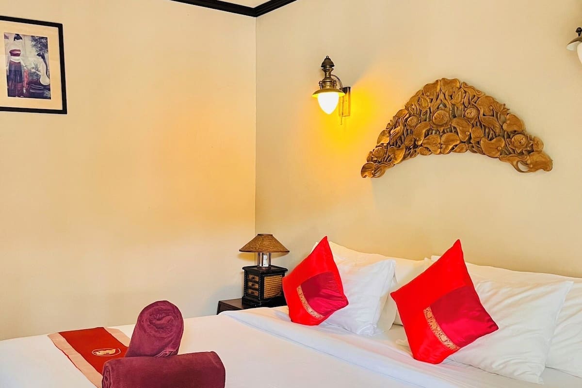 A hotel room with a bed, a nightstand, a lamp, and a wall decoration.