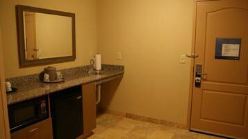 A compact kitchen with a microwave, coffee maker, and sink.