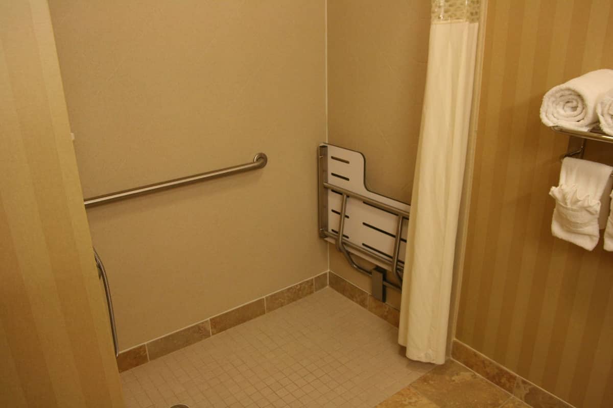 A bathroom with a grab bar, a shower curtain, and a towel rack.