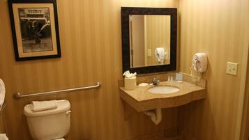 A bathroom with a toilet, sink, mirror, and hand dryer.