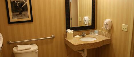 A bathroom with a toilet, sink, mirror, and hand dryer.