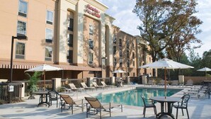 A hotel with a pool area, outdoor seating, and a sign reading "Hampton Inn & Suites". - Hampton Inn & Suites Mobile Providence Park/Airport (Mobile)