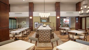 A spacious restaurant with high ceilings, multiple dining tables, and a central decorative island. - Hampton Inn & Suites Mobile Providence Park/Airport (Mobile)
