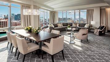 A modern living room with a dining area, large windows, and a city view.