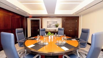 Une salle de conférence avec une table ronde, des chaises bleues et une plante servant de décoration centrale.