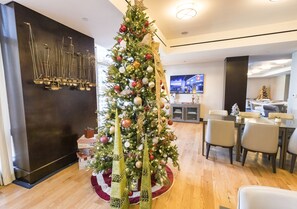 A modern hotel lobby with a large Christmas tree, wooden flooring, and a dining area with chairs and tables. - InterContinental Boston by IHG (Boston)