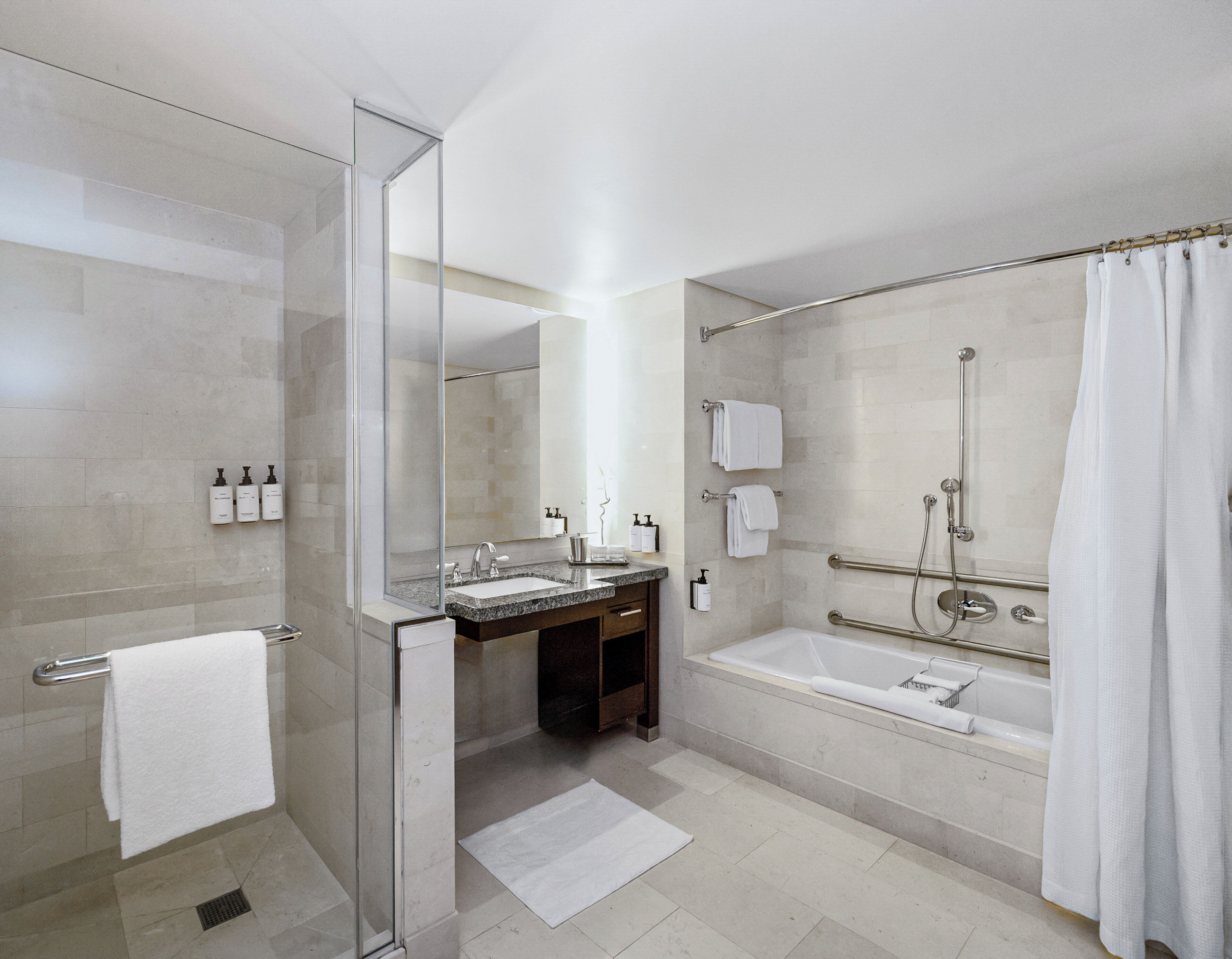 A modern bathroom with a glass shower enclosure, a bathtub, and a vanity with a sink and mirror.