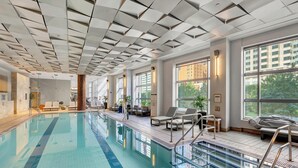 A modern indoor swimming pool with clear blue water, sunlit windows, and lounge chairs along the poolside. - InterContinental Boston by IHG (Boston)