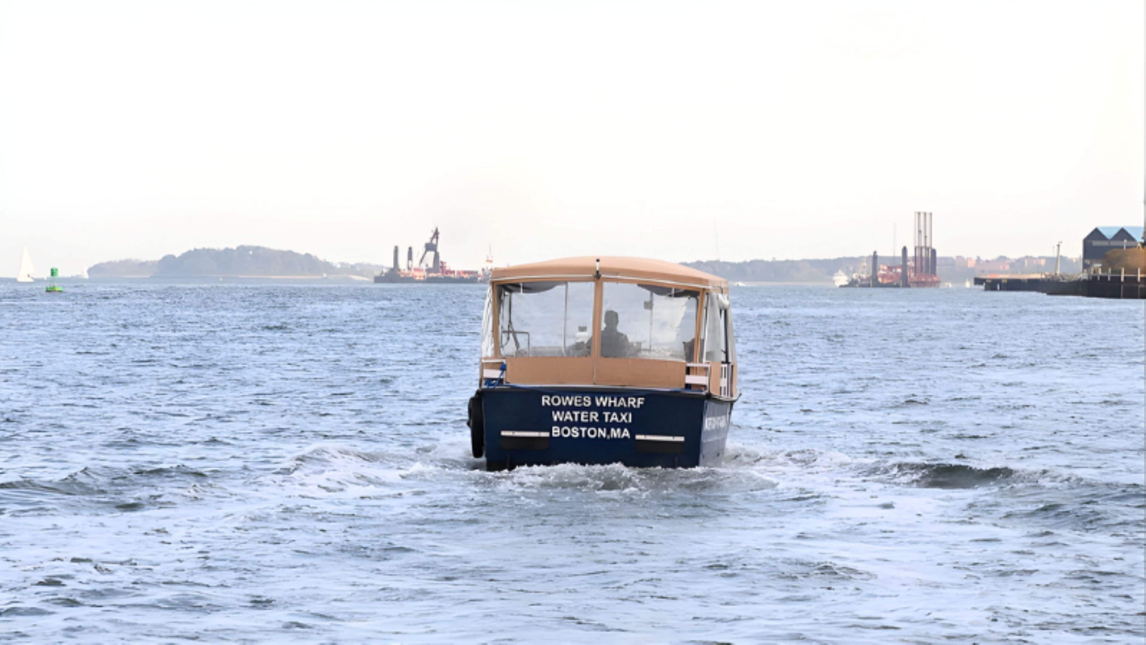 A water taxi with 'Rowes Wharf Water Taxi Boston, MA' written on the side.