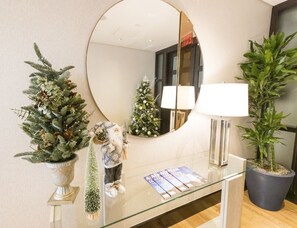 A lobby with a round mirror, a Christmas tree, a gnome decoration, a lamp, and a potted plant. - InterContinental Boston by IHG (Boston)