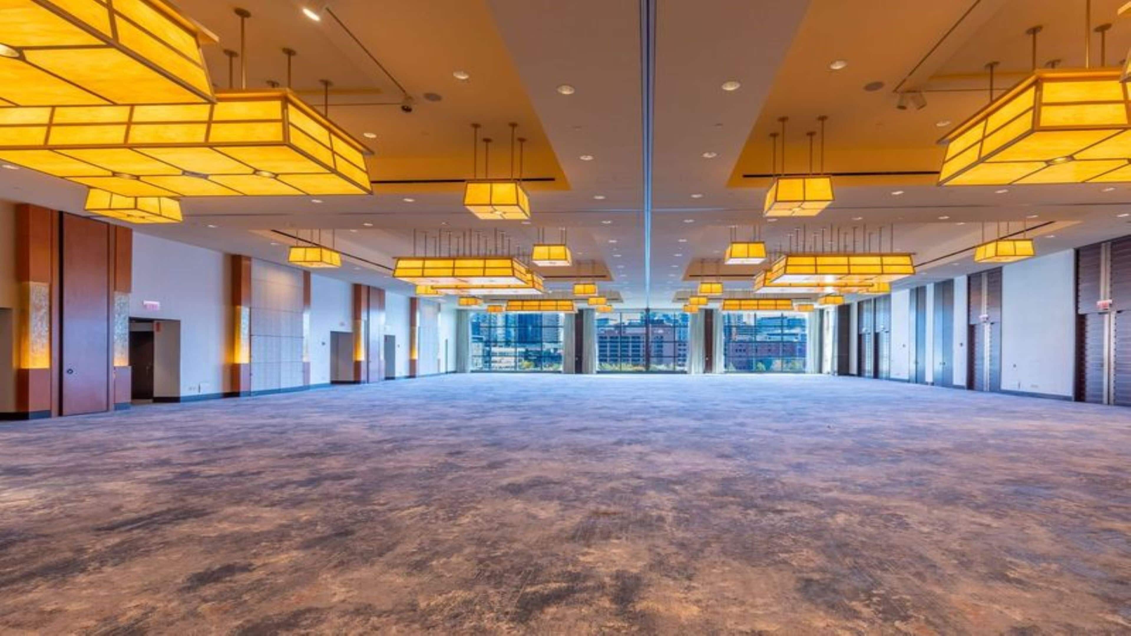 A spacious indoor area with a high ceiling and multiple hanging light fixtures.