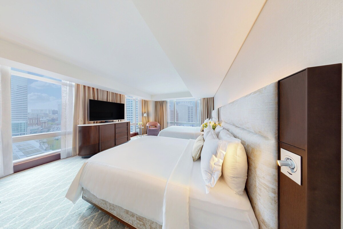 Una habitación de hotel moderna con una cama grande, un televisor de pantalla plana, un escritorio y vistas a la ciudad.