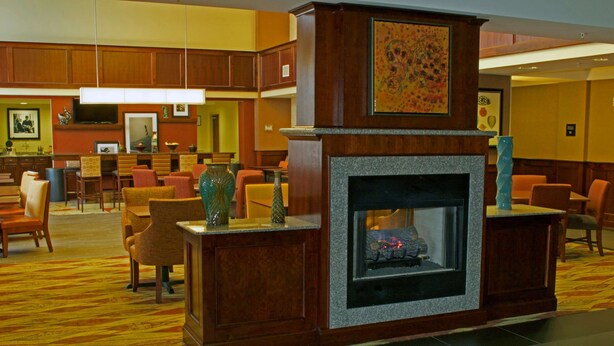 A lobby with a fireplace, seating area, and a television. - Hampton Inn & Suites Norfolk-Airport (Norfolk)