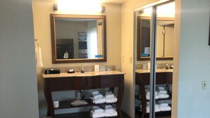 A hotel bathroom with a vanity, mirror, and shelves with towels. - Hampton Inn & Suites Norfolk-Airport (Norfolk)