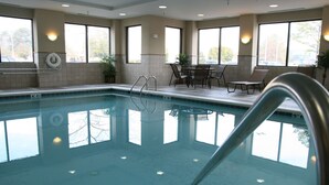 A swimming pool with clear water, surrounded by windows and a seating area with chairs and tables. - Hampton Inn & Suites Norfolk-Airport (Norfolk)