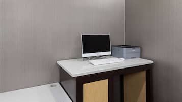 Un escritorio con una computadora e impresora en una habitación con pared texturizada.