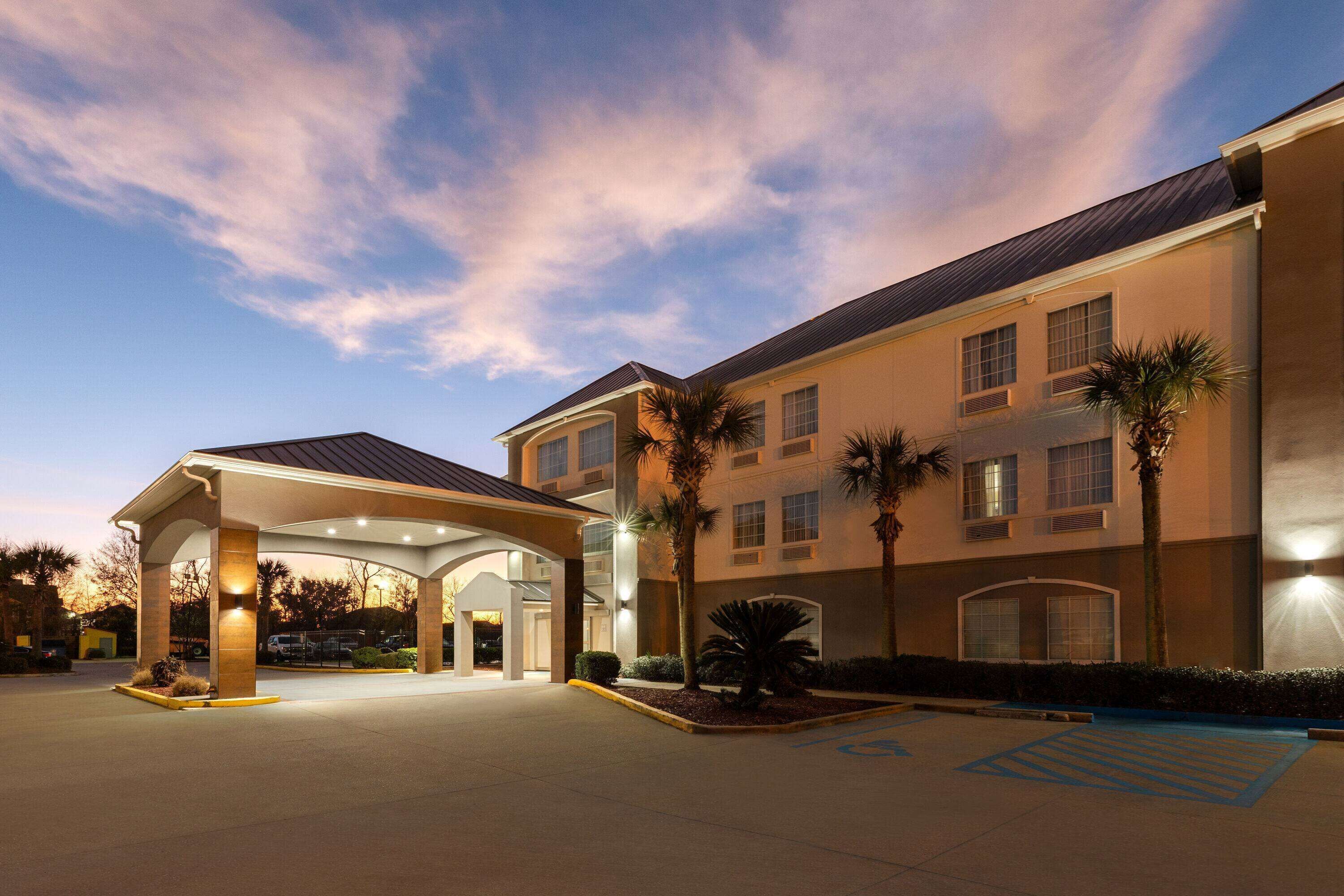 A hotel with a covered entrance, palm trees, and a parking area with handicapped accessibility.