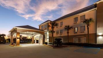 A hotel with a covered entrance, palm trees, and a parking area with handicapped accessibility.