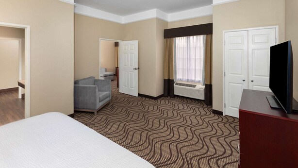 A hotel room with a bed, a desk, a television, and a window with curtains. - La Quinta Inn & Suites by Wyndham Houma (Houma)