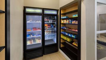 A section of a store with two refrigerated display cases labeled "Bright Side Market" and shelves stocked with snacks and beverages.