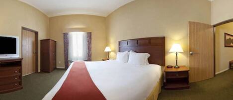 A hotel room with a large bed, two bedside tables with lamps, a television, a wardrobe, and a door leading to another room.