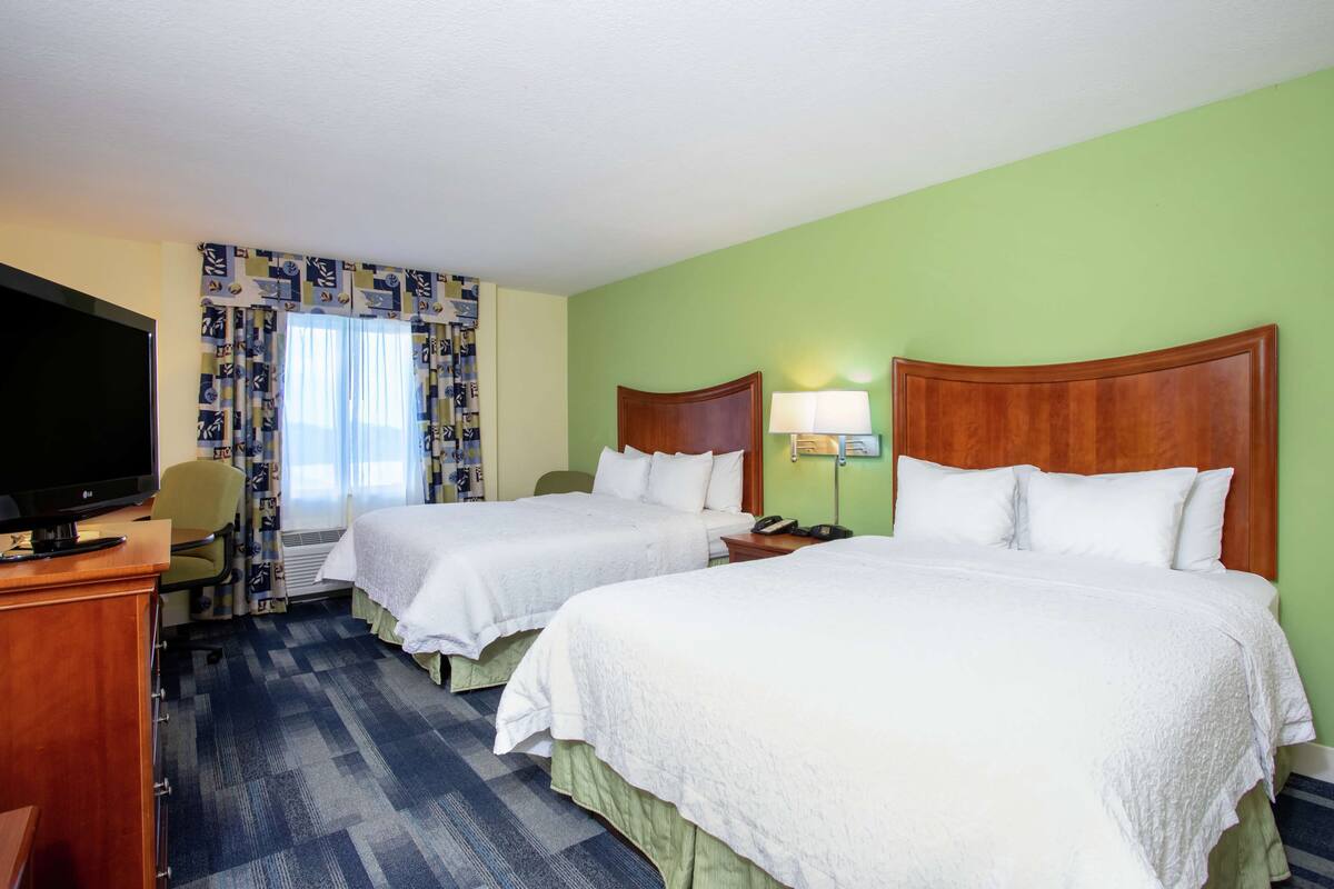 Une chambre d’hôtel avec deux lits, une télévision, un bureau et une chaise.