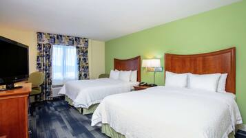 A hotel room with two beds, a television, a desk, and a chair.