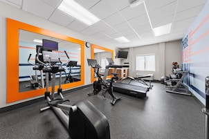 Un gimnasio con equipo de ejercicio, espejos y decoración inspiradora en las paredes.